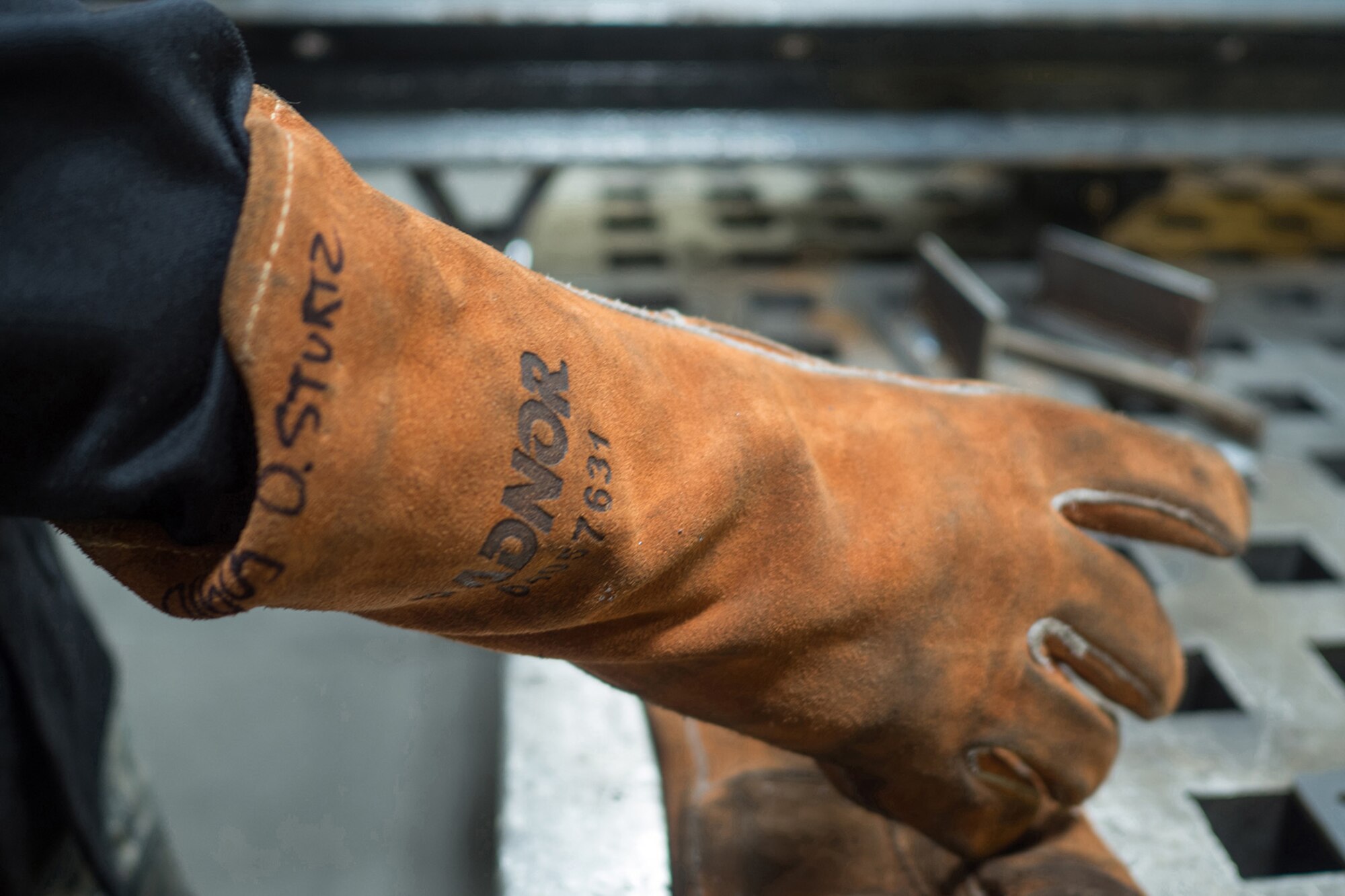 Airman Dalton Sturtz, a native of Seguin, Texas, an aircraft metals technology journeyman assigned to the 3rd Maintenance Squadron, takes off his protective gloves after welding a metal plate in the metals fabrication shop on Joint Base Elmendorf-Richardson, Alaska, May 9, 2018. Aircraft Metals Technology Airmen measure broken or worn parts, draw working sketches, make templates, perform precision grinding remove poisonous or corrosive deposits from parts, and write programs for machines using manual and computer-aided manufacturing.