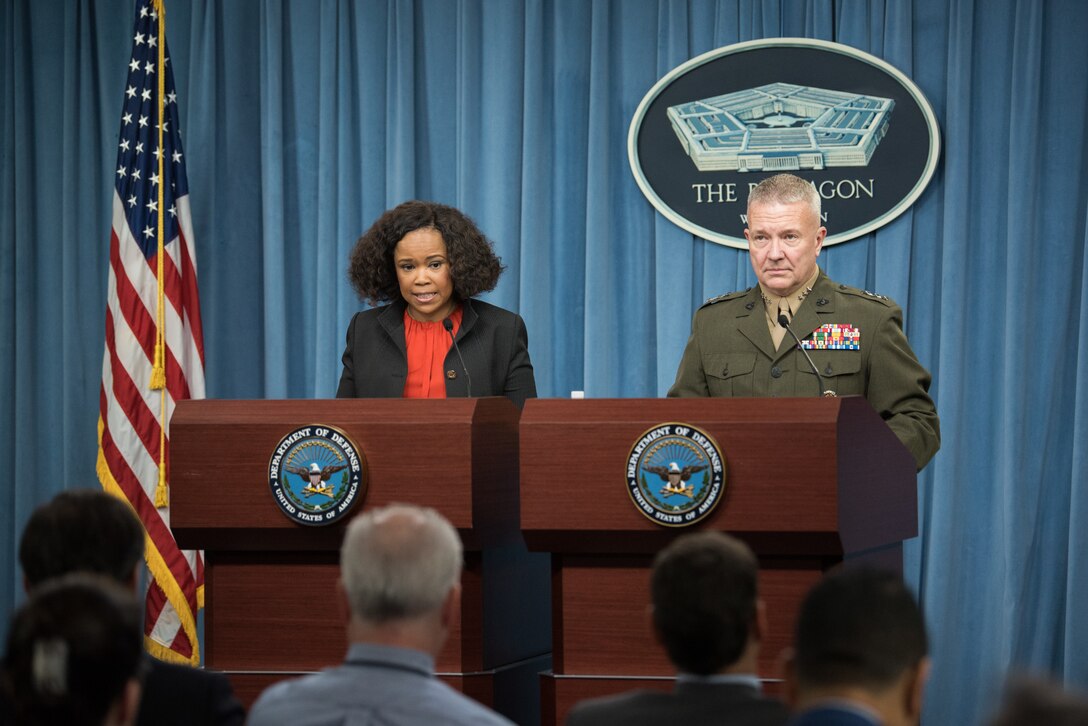A man and a woman stand at podiums at the Pentagon.