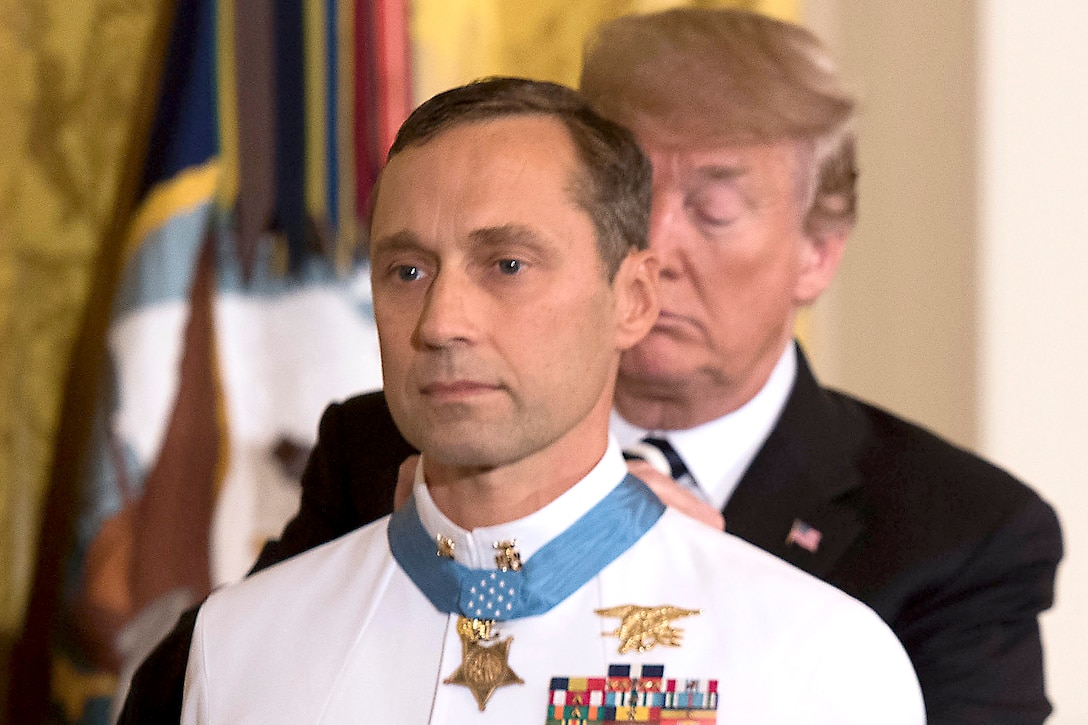 The president places the Medal of Honor on a sailor.