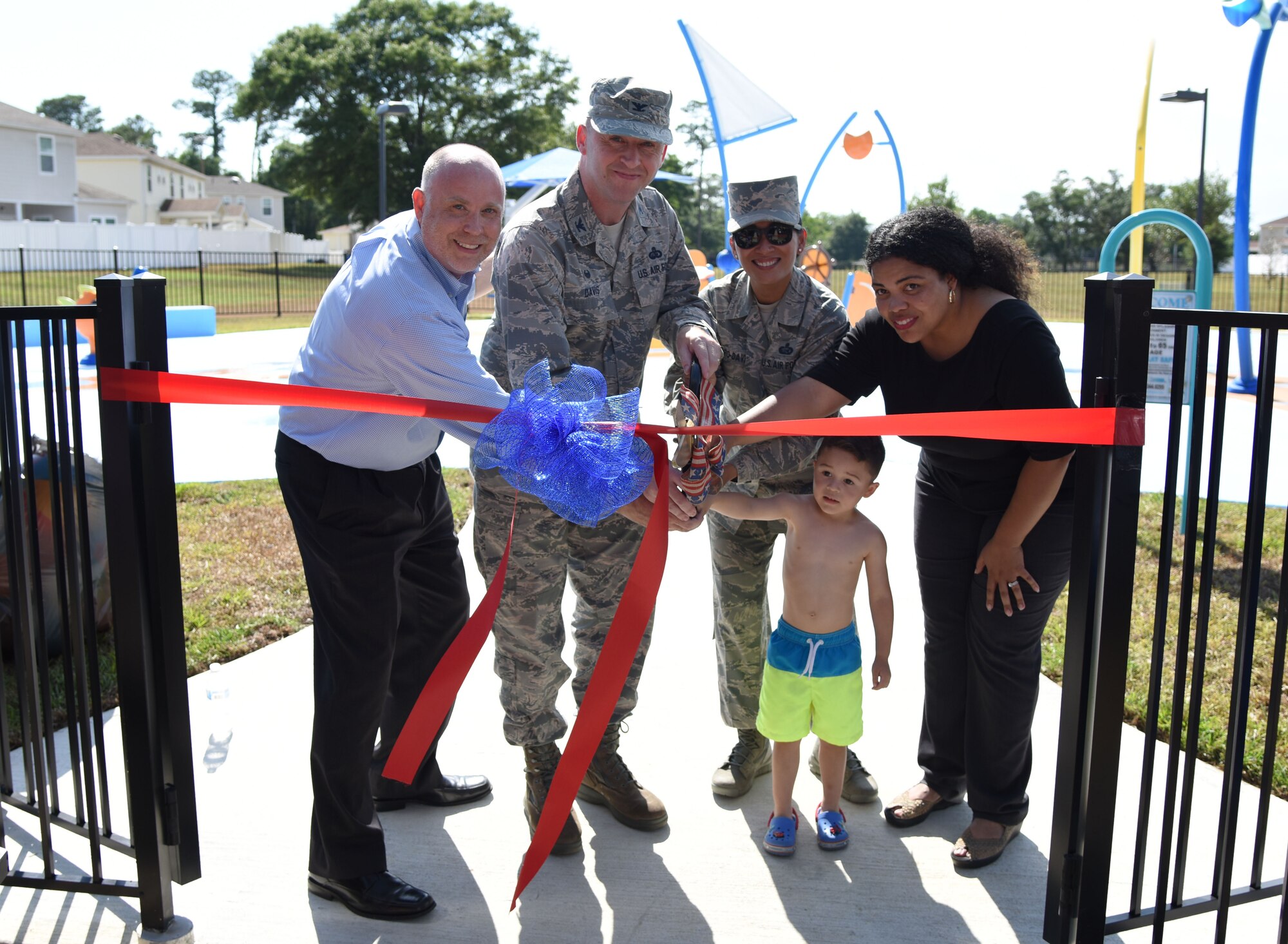 U.S. Air Force Col. Danny Davis, 81st Mission Support Group commander,  helps cut a ribbon during the Splash Pad Ribbon Cutting Ceremony at the West Falcon Housing area in Biloxi, Mississippi, May 22, 2018. The Hunt Company project will provide more recreational activities for all Keesler family housing families. (U.S. Air Force photo by Kemberly Groue)