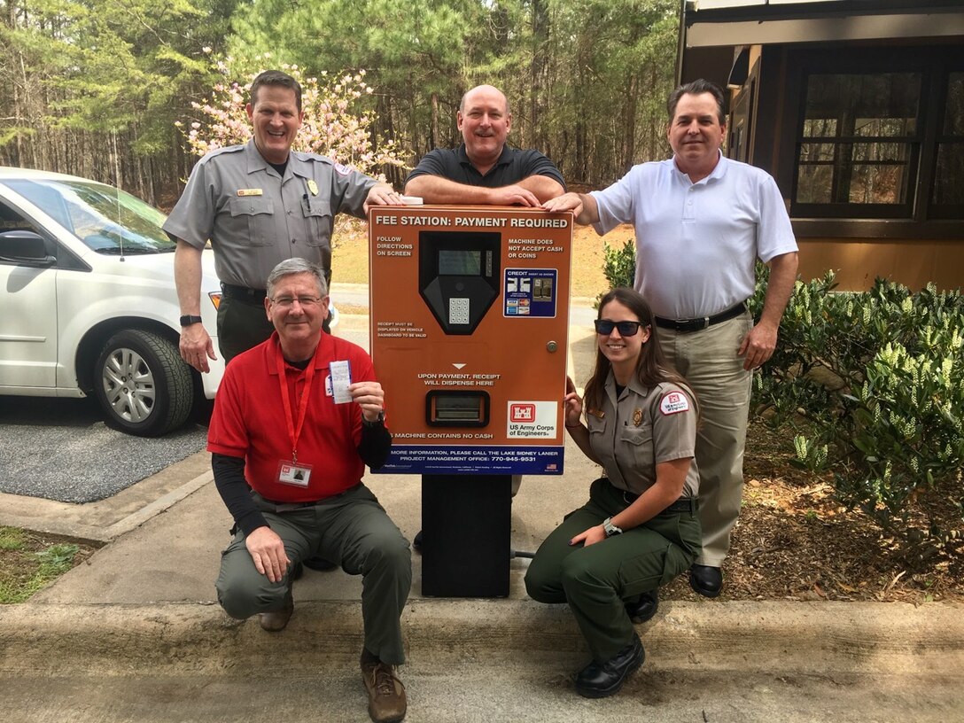 Employees of the U.S. Army Corps of Engineers Lake Sidney Lanier office pose by one of the new automated fee payment machines at Lake Sidney Lanier, Ga., on May 21, 2018.