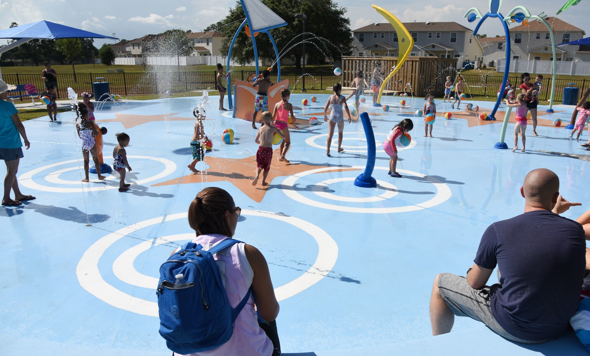 Military children play on the splash pad during the Splash Pad Ribbon Cutting Ceremony at the West Falcon Housing area in Biloxi, Mississippi, May 22, 2018. The Hunt Company project will provide more recreational activities for all Keesler family housing families. (U.S. Air Force photo by Kemberly Groue)