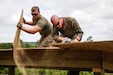 U.S. Marines Lance Cpl. Caleb J. Malone (left), combat engineer with Bridge Company C, 6th Engineer Support Battalion, 4th Marine Logistics Group, discards a piece of cut plywood as Lance Cpl. Matthew P. Winter (right), combat engineer with Engineer Company C, 6th ESB, 4th MLG, cuts plywood with a circular saw at a construction site during exercise Red Dagger at Fort Indiantown Gap, Pa., May 23, 2018.