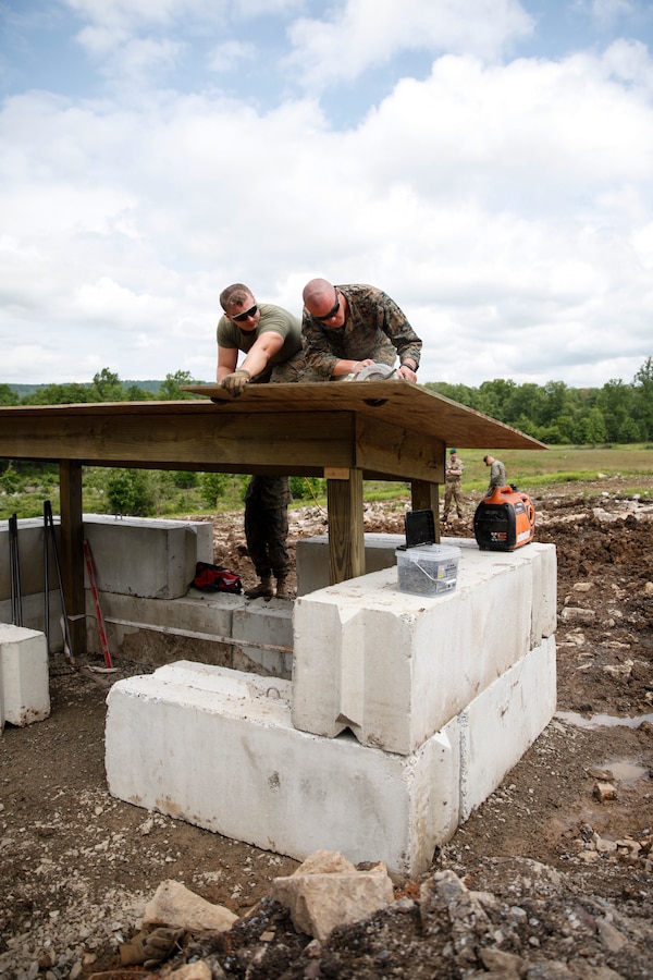 U.S. Marines Lance Cpl. Caleb J. Malone (left), combat engineer with Bridge Company C, 6th Engineer Support Battalion, 4th Marine Logistics Group, holds a piece of plywood as Lance Cpl. Matthew P. Winter (right), combat engineer with Engineer Company C, 6th ESB, 4th MLG, cuts plywood with a circular saw at a construction site during exercise Red Dagger at Fort Indiantown Gap, Pa., May 23, 2018. Exercise Red Dagger is a bilateral training exercise that gives Marines an opportunity to exchange tactics, techniques and procedures as well as build working relationships with their British counterparts. (U.S. Marine Corps photo by Sgt. Melanie Wolf/Released)