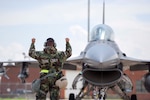 An Airman with the 180th Fighter Wing maintenance group uses hand signals to direct an F-16 Fighting Falcon during a training exercise on May 19, 2018. Airmen wore Mission-Oriented Personal Protective gear while maintaining, launching and recovering aircraft to simulate operating in an environment in which a chemical attack occurred.