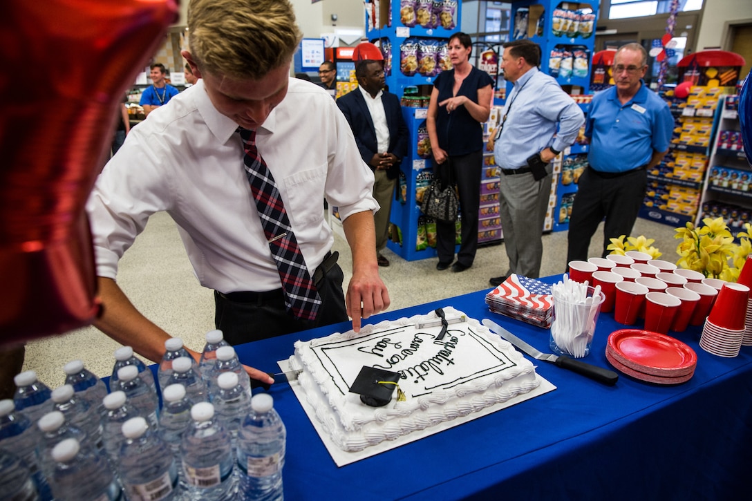 Cameron Lay, a student at Yucca Valley High School, cuts a cake during his award ceremony at the Commissary aboard the Marine Corps Air Ground Combat Center, Twentynine Palms, Calif., May 17, 2018. Defense Commissary Agency partnered with Fisher House, an organization that focuses on administering scholarships for military children, to award Lay for his outstanding academic achievements and service to the community. (U.S. Marine Corps photo by Lance Cpl. Margaret Gale)