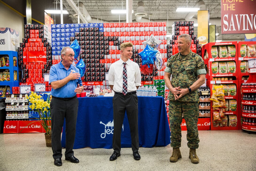 Maj. Gen. William F. Mullen III, commanding general, Marine Corps Air Ground Combat Center, presents Cameron Lay, a student at Yucca Valley High School, with a college scholarship from Fisher House Foundation at the Commissary aboard the Combat Center, Twentynine Palms, Calif., May 17, 2018. Defense Commissary Agency partnered with Fisher House, an organization that focuses on administering scholarships for military children, to award Lay for his outstanding, academic achievements and service to the community. (U.S. Marine Corps photo by Lance Cpl. Margaret Gale)