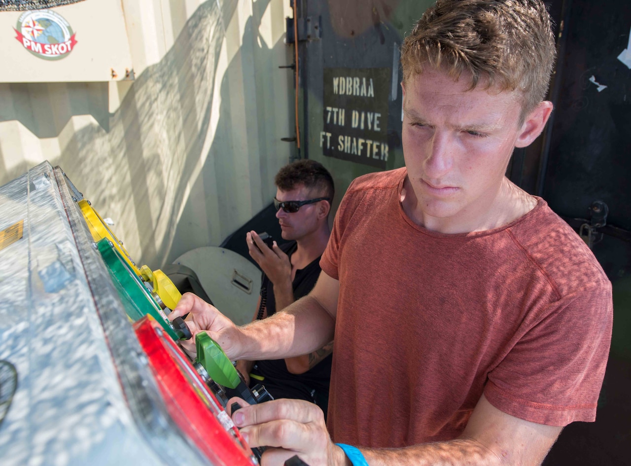 Army Spc. Timothy Sparks, a diver with the 7th Engineer Dive Detachment, monitors the air levels of two divers during an underwater recovery mission near Nha Trang, Vietnam.