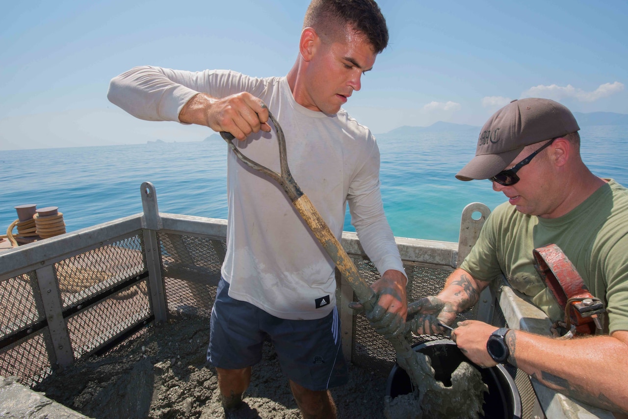 Army Sgt. Eoin Audet, a diver with the 7th Engineer Dive Detachment, shovels sediment out of a metal basket into buckets that are screened as part of an underwater recovery mission near Nha Trang, Vietnam.