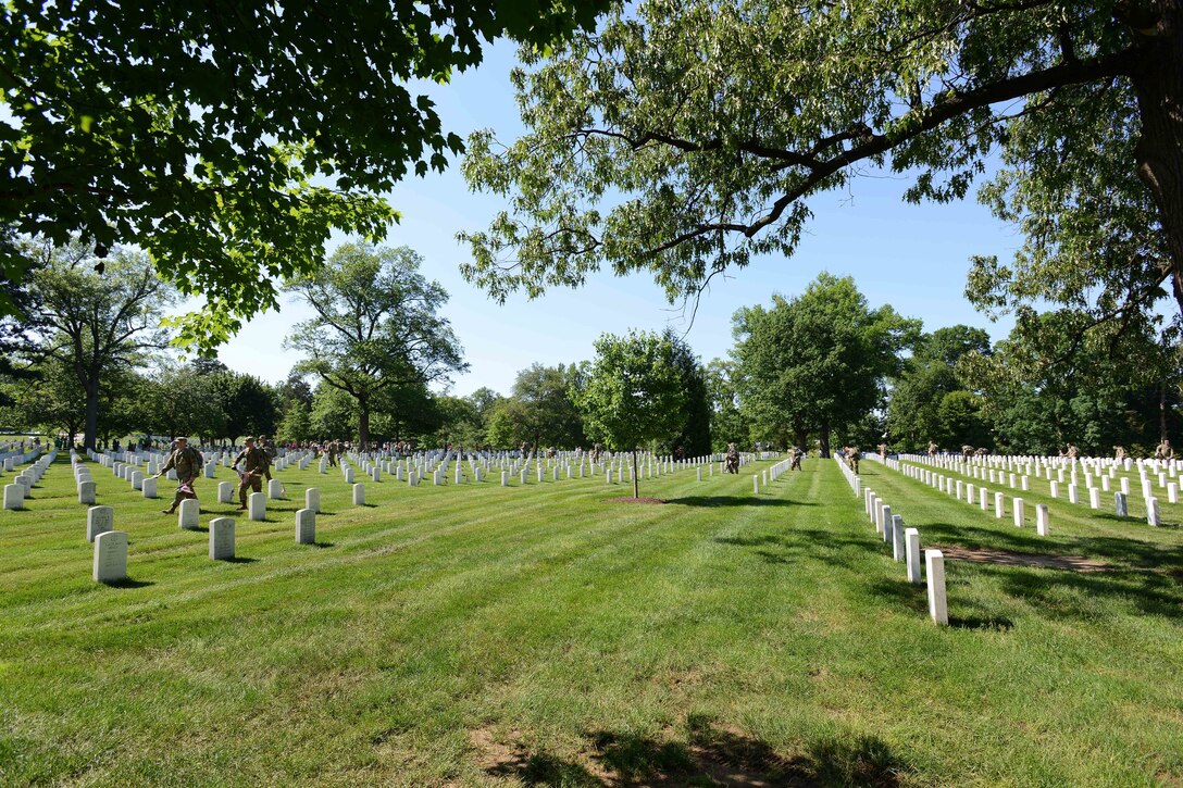 Soldiers place American flags in front of headstones.