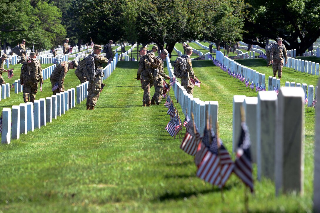 Soldiers place American flags in front of headstones during "Flags In."