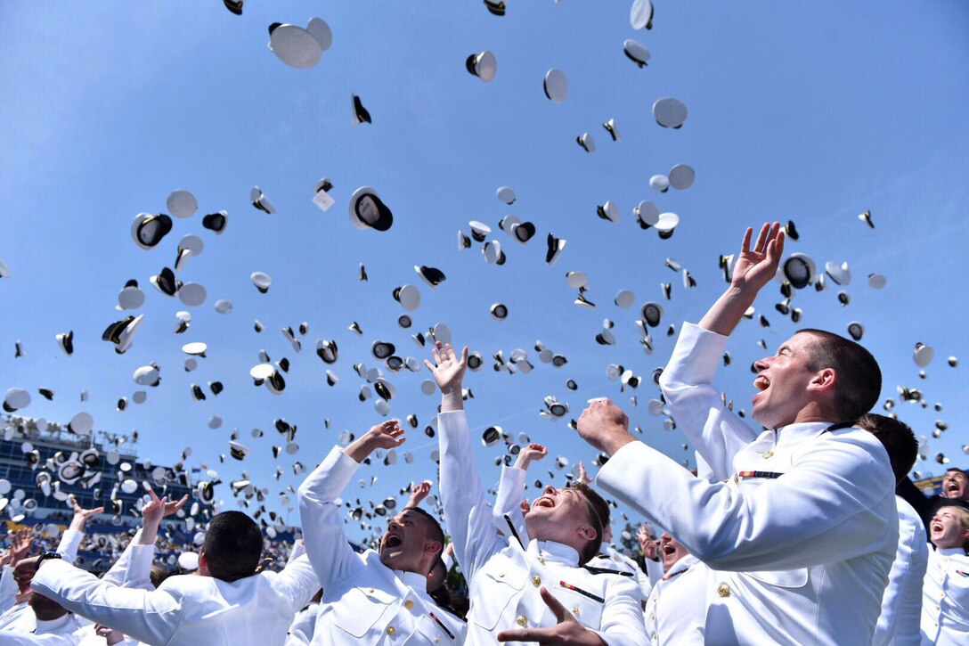 Sailors and Marines toss hats into the air.