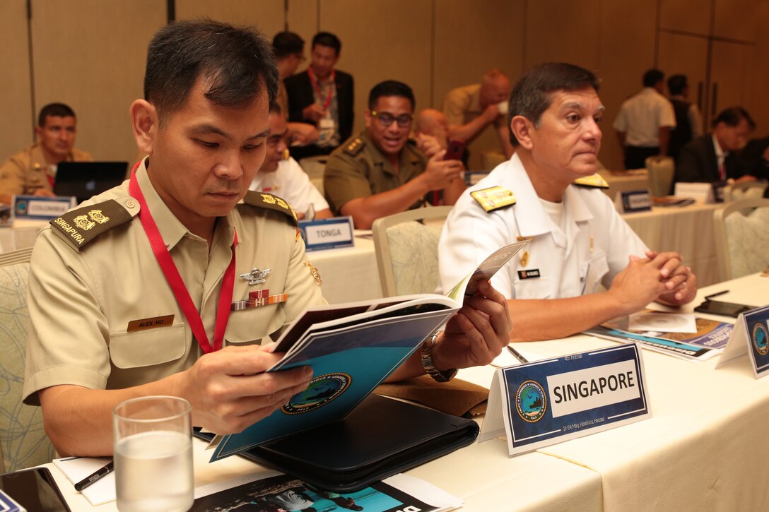Singapore Armed Forces Lt. Col. Alex Ho, Liasion Officer to the U.S. Marine Corps, flips through the Pacific Amphibious Leaders Symposium (PALS) photo book during PALS in Honolulu, Hawaii, May 23, 2018.
