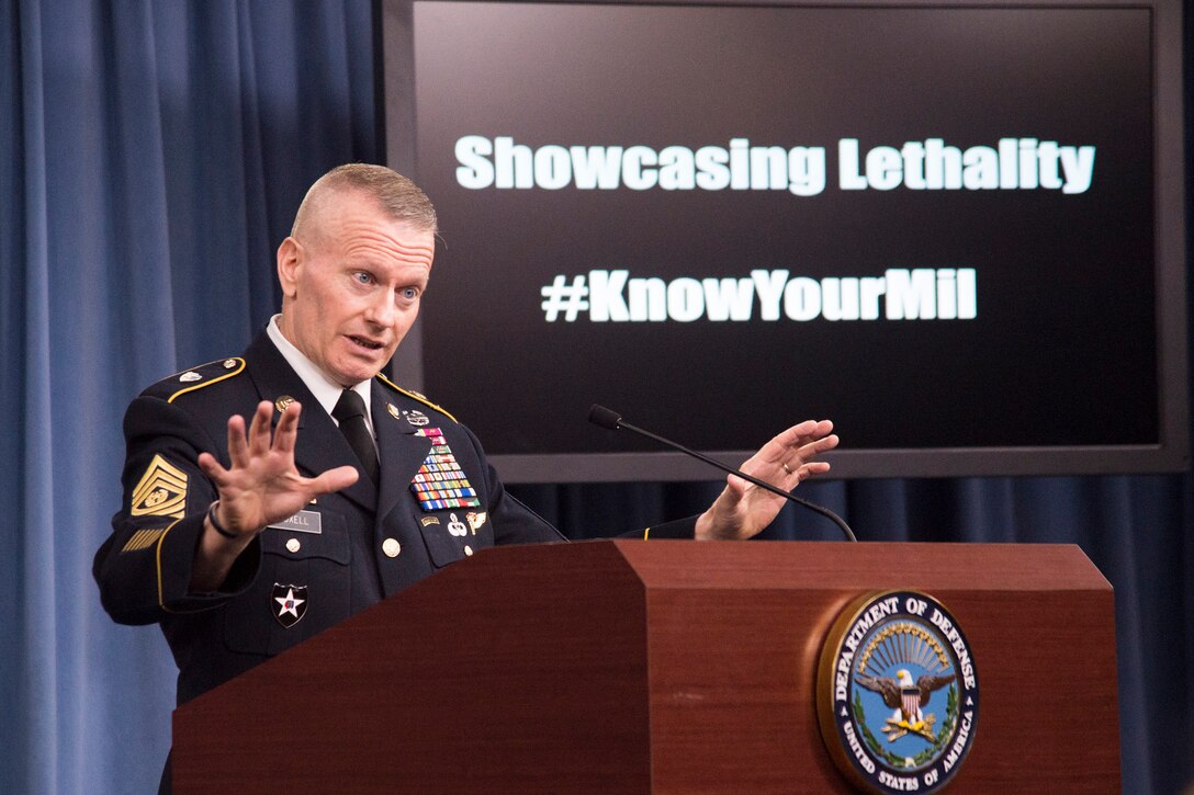 Army Command Sgt. Maj. John W. Troxell gestures while speaking at a lectern.