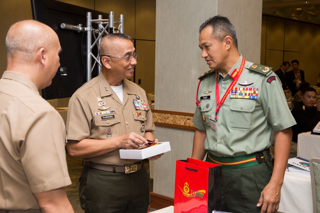 Philippine Marine Corps Maj. Gen. Alvin A. Parreno, center, commandant, Philippine Marine Corps, receives a gift from Malaysian Brig. Gen. Tengku Muhammad Fauzi Tengku Ibrahim, right, commander, 10th Brigade, during the Pacific Amphibious Leaders Symposium (PALS) 2018 in Honolulu, Hawaii, May 24, 2018. PALS brings together senior leaders of allied and partner militaries with significant interest in the security and stability of the Indo-Pacific region to discuss key aspects of maritime/amphibious operations, capability development, crisis response and interoperability. (U.S. Marine Corps photo by Cpl. Patrick Mahoney)