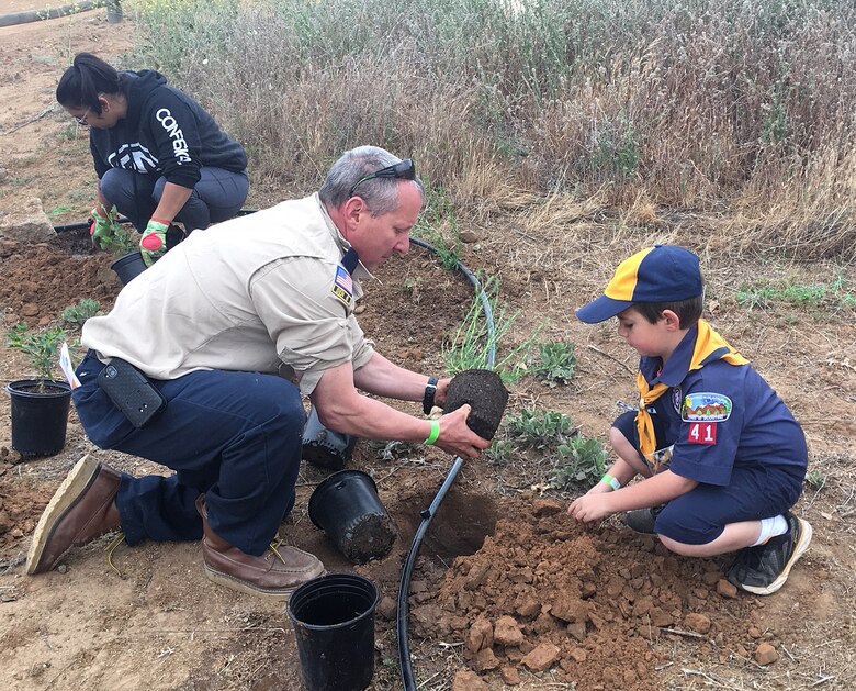 A Cub Scout and his leader help plant native vegetation near the Santa Ana River during a May 12 planting event in Norco, California.