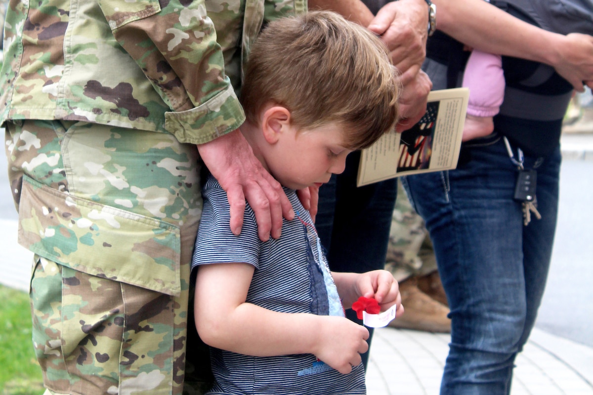 A child holds a red flower.