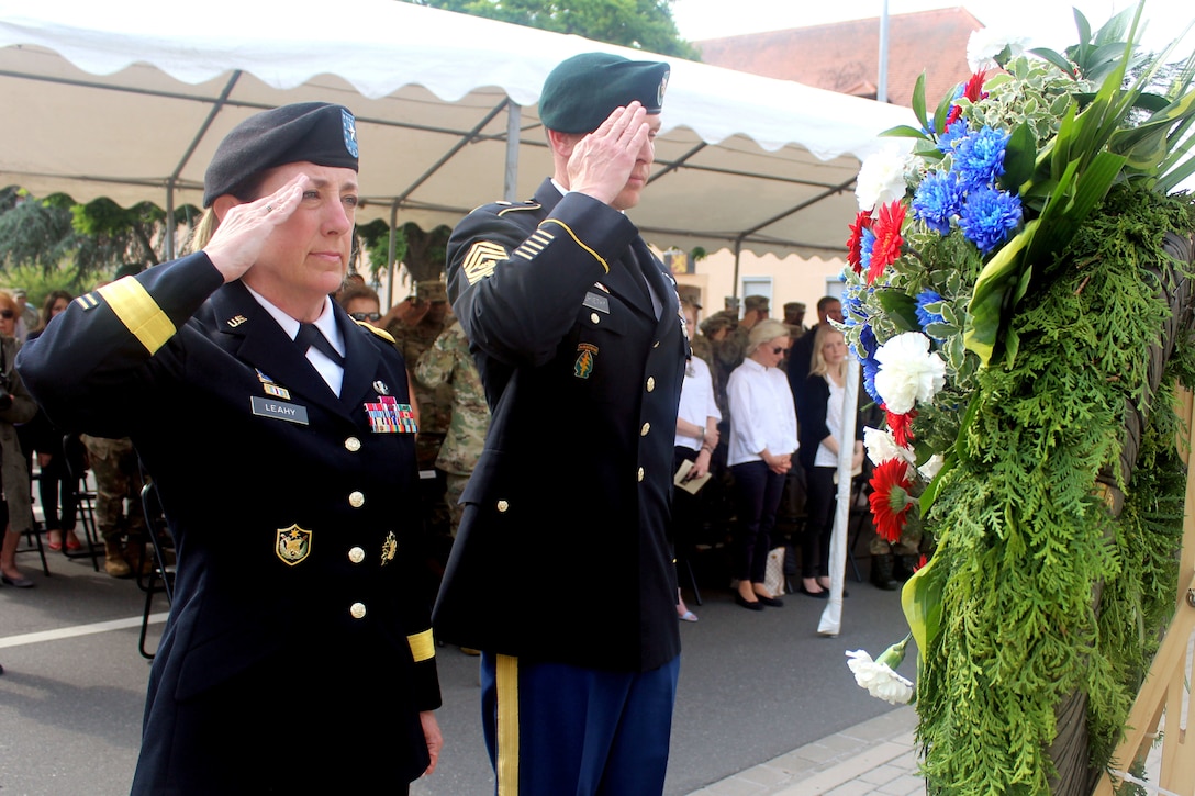 Two soldiers salute a wreath.