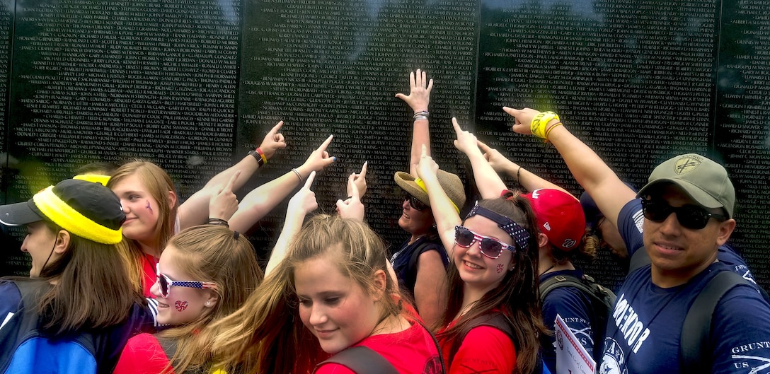 A group of 13 to 15 year olds attending the Tragedy Assistance Program for Survivor’s 24th annual National Military Survivor Seminar and Good Grief Camp, along with their mentors, point to the name of Air Force Col. Charles Stoddard Rowley, father of mentor Patti Rowley, at the Vietnam Veterans Memorial wall in Washington.
