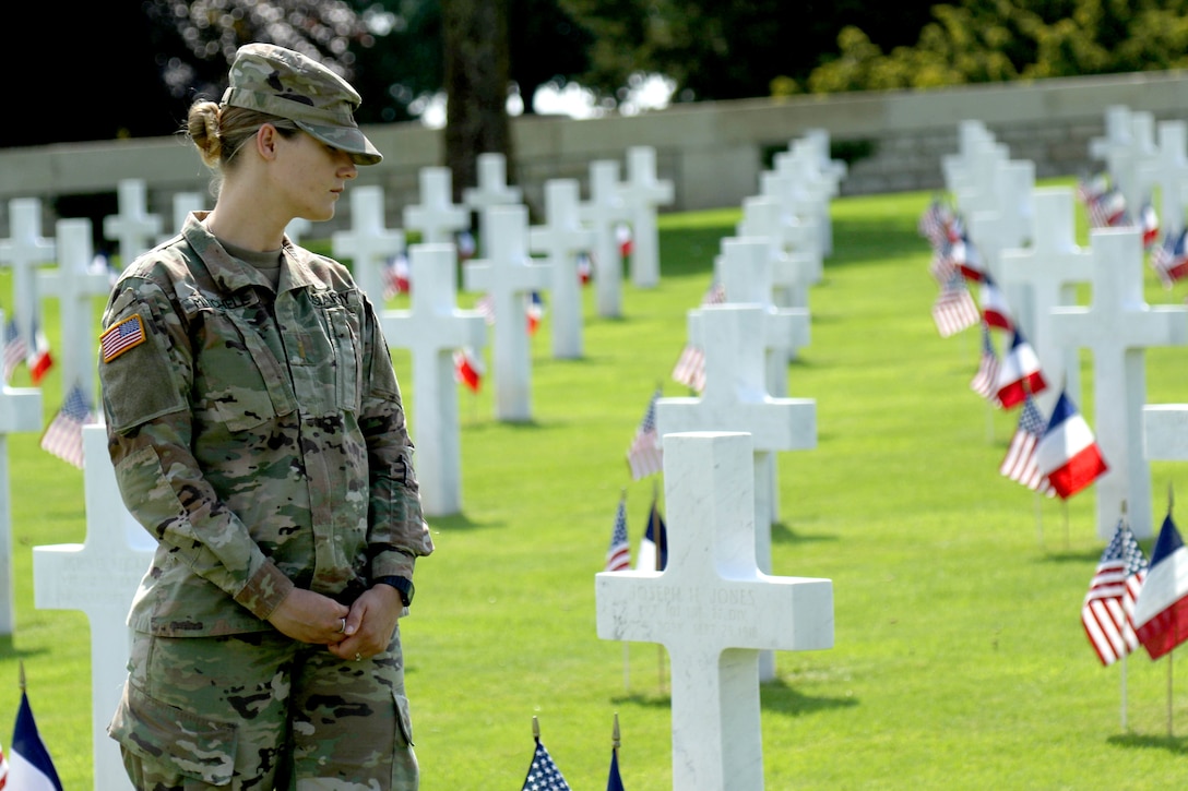 A soldier looks at cross shaped headstones.