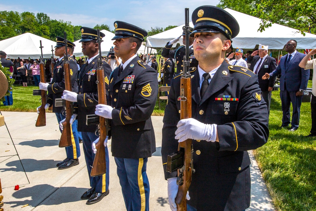 A row of soldiers hold weapons during a ceremony.