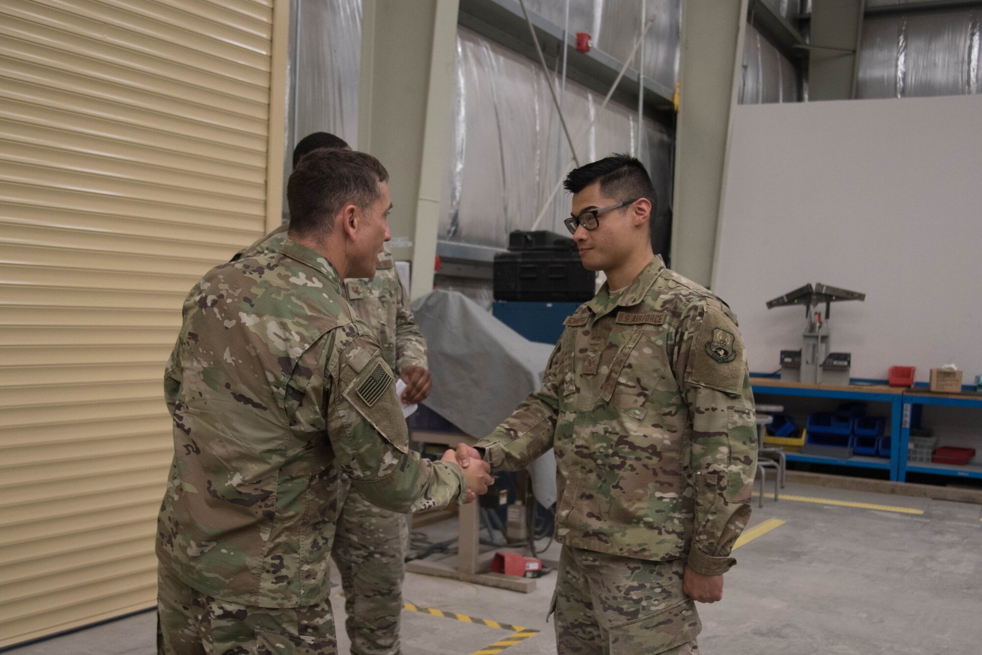 U.S. Air Force Chief Master Sgt. Joseph Montgomery, U.S. Air Forces Central Command Chief, coins Staff Sgt. Andrew Schaeffer, 380th Expeditionary Maintenance Squadron aircrew egress technician, for his outstanding performance while deployed to Al Dhafra Air Base, May 25. (U.S. Air Force photo by Staff Sgt. Erica Rodriguez)