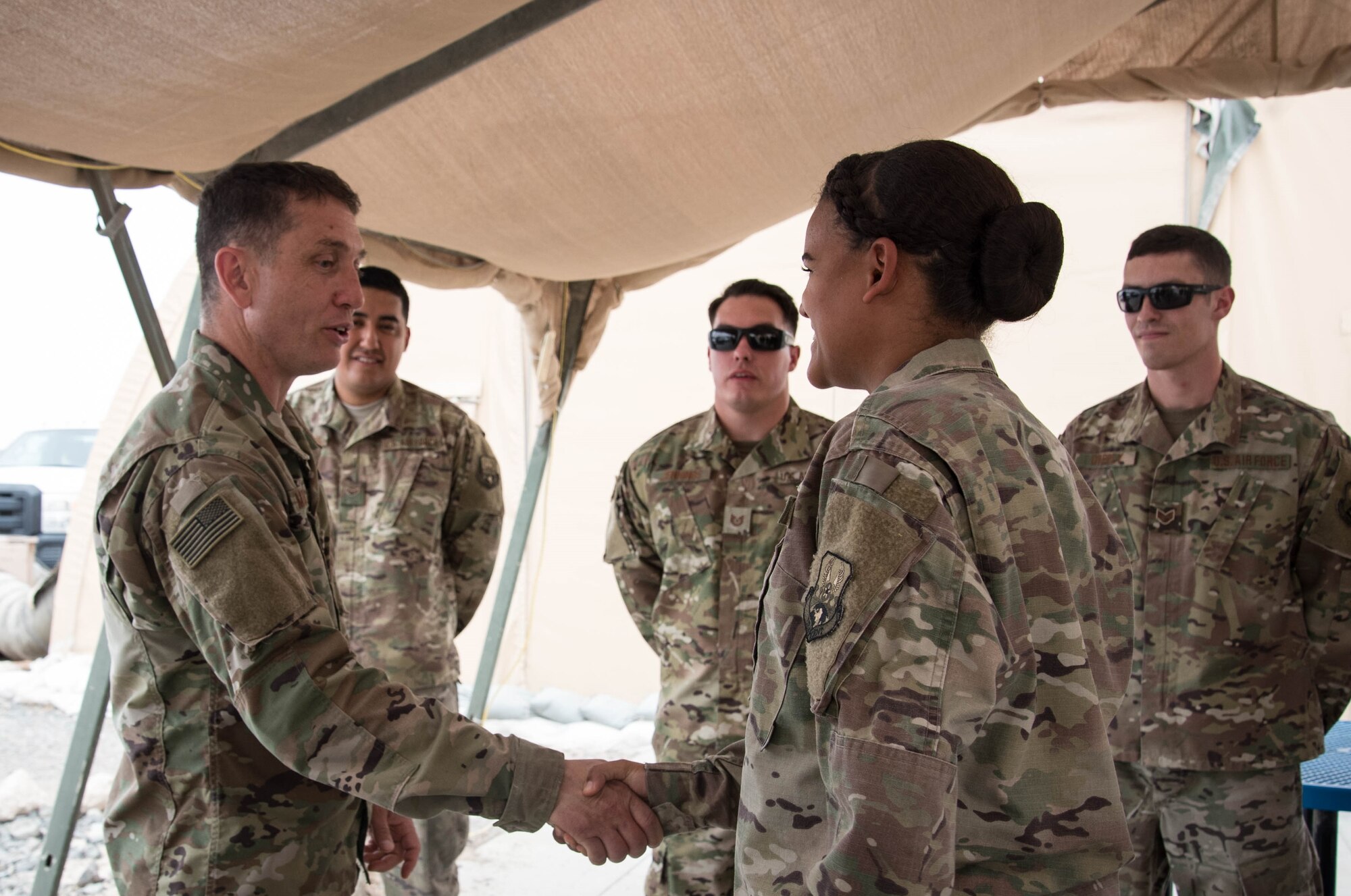 U.S. Air Force Chief Master Sgt. Joseph Montgomery, U.S. Air Forces Central Command Chief, coins Airman 1st Class Alana Misenti, 380th Expeditionary Maintenance Squadron precision guided munitions crew chief, for her outstanding performance while deployed to Al Dhafra Air Base, May 25. (U.S. Air Force photo by Staff Sgt. Erica Rodriguez)