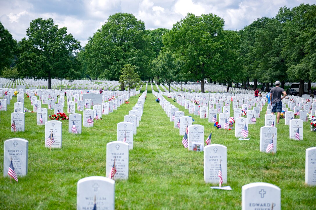 Flags and mementos sit on rows of headstones.