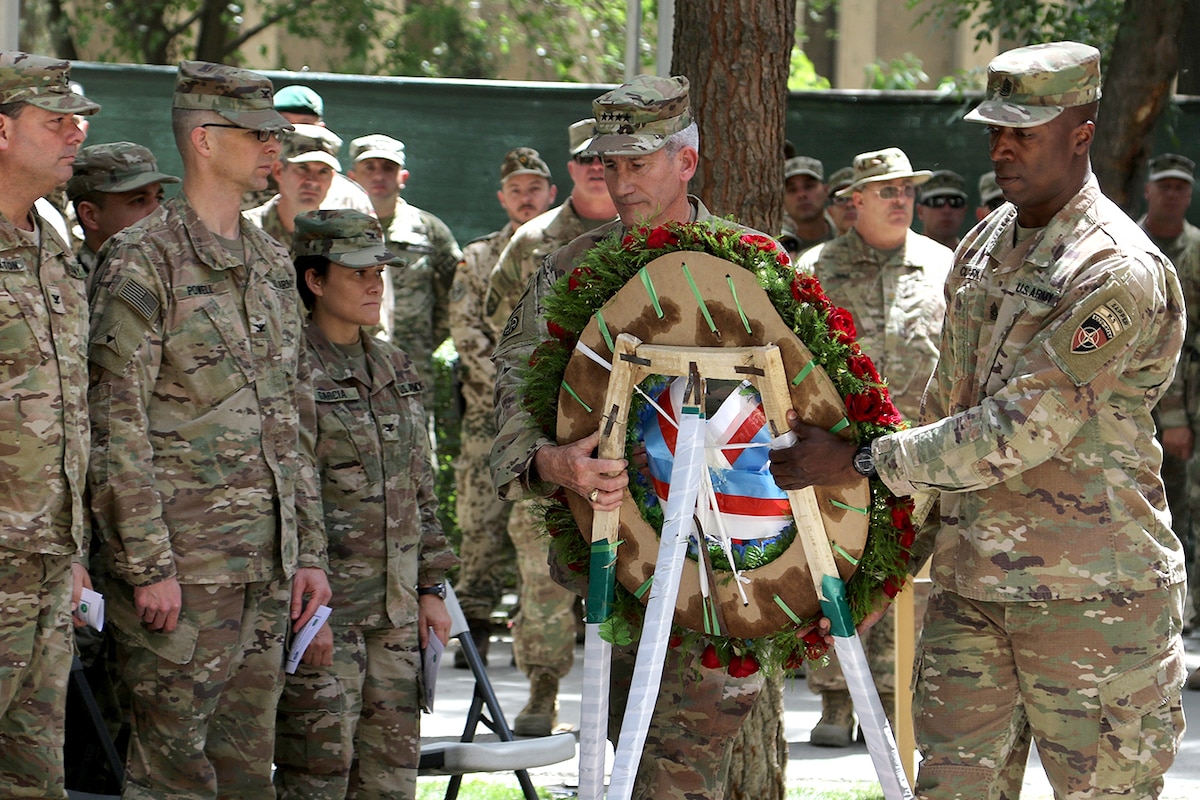 Two soldiers carry a wreath.