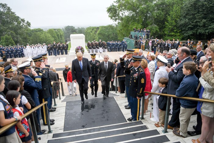 The president, defense secretary and others walk up steps.