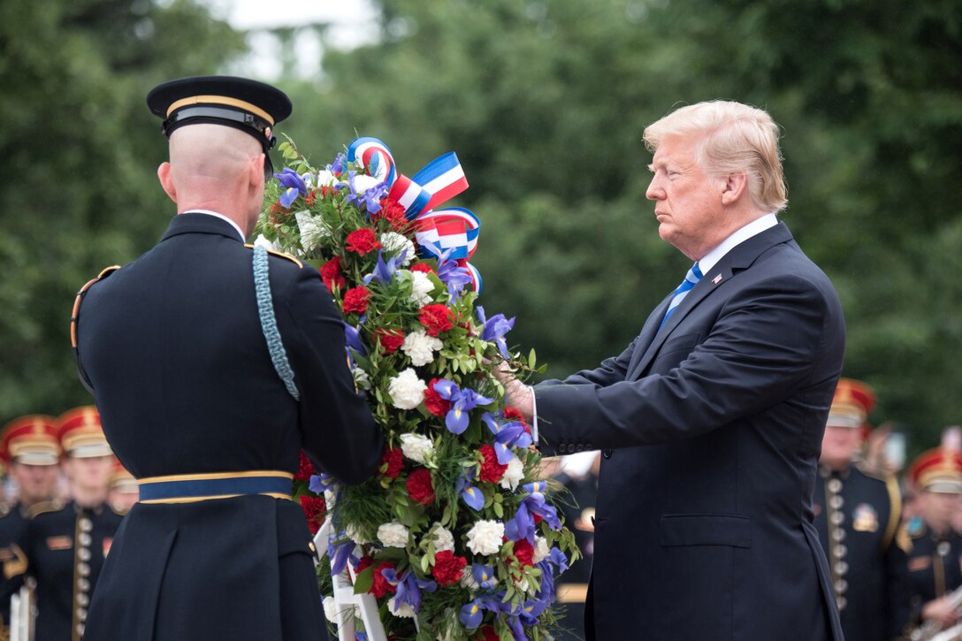 The president places a wreath with the help of a soldier.