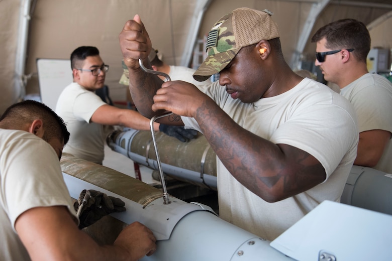 Airmen with the 332nd Expeditionary Maintenance Squadron Munitions Flight builds bombs for the F-15E at an undisclosed location in Southwest Asia May 19, 2018.