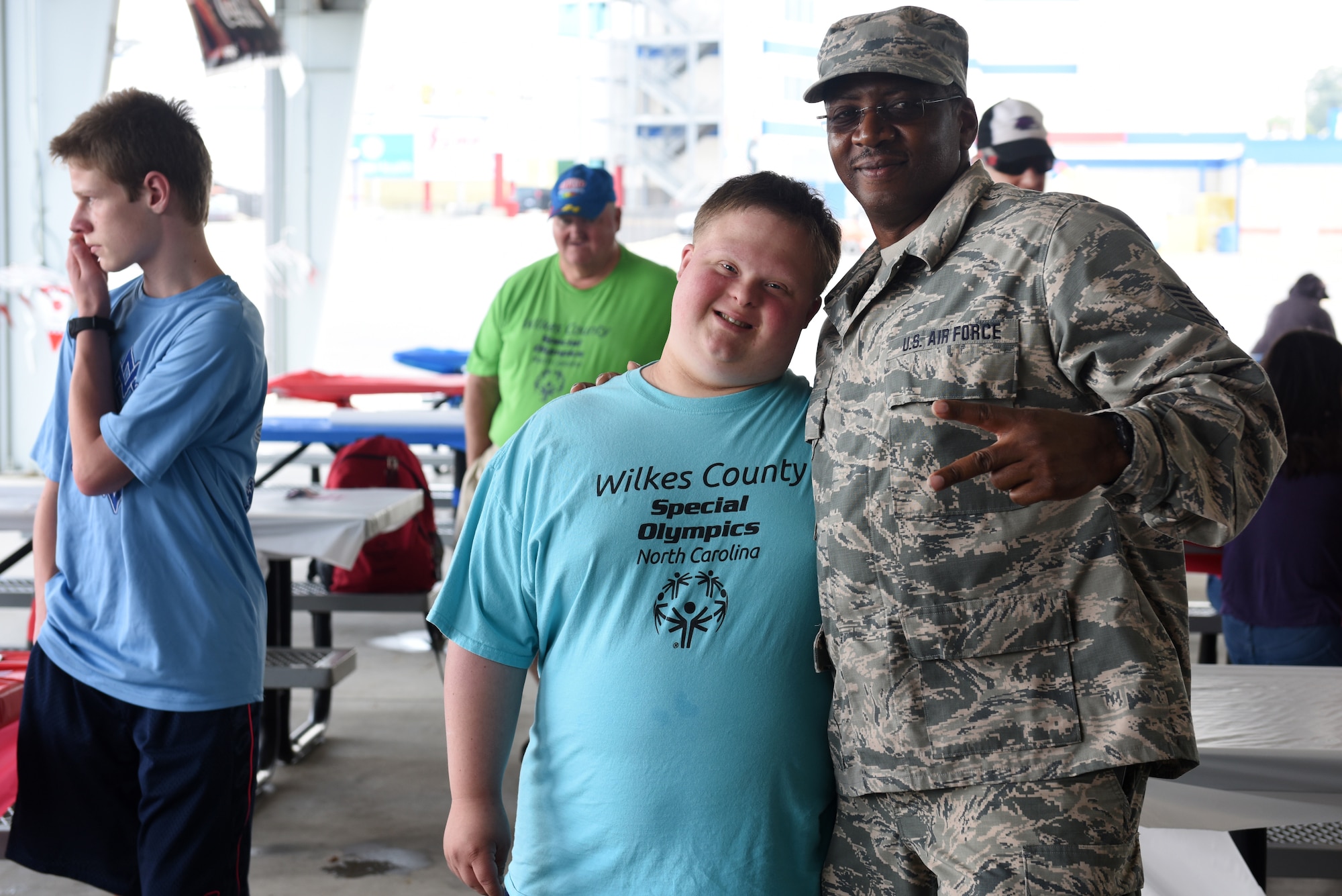 U.S. Air Force Tech. Sgt. Aldrich Cherry, information management with the 145th Maintenance Squadron, poses with athletes at the Z-Max Pavilion, Charlotte N.C., during the annual Special Olympics Day at the Races, May 24, 2018. The Special Olympics Day at the Races is an annual celebration held at the Lowes Motor Speedway and is put on by Vangie Boswell and fourteen sponsors including the North Carolina Air National Guard (NCANG). Members of the NCANG help set-up the event and pass out mementos while mingling with State Special Olympians and their families.(U.S. Air Force photo by Staff Sgt. Laura J. Montgomery/Released)