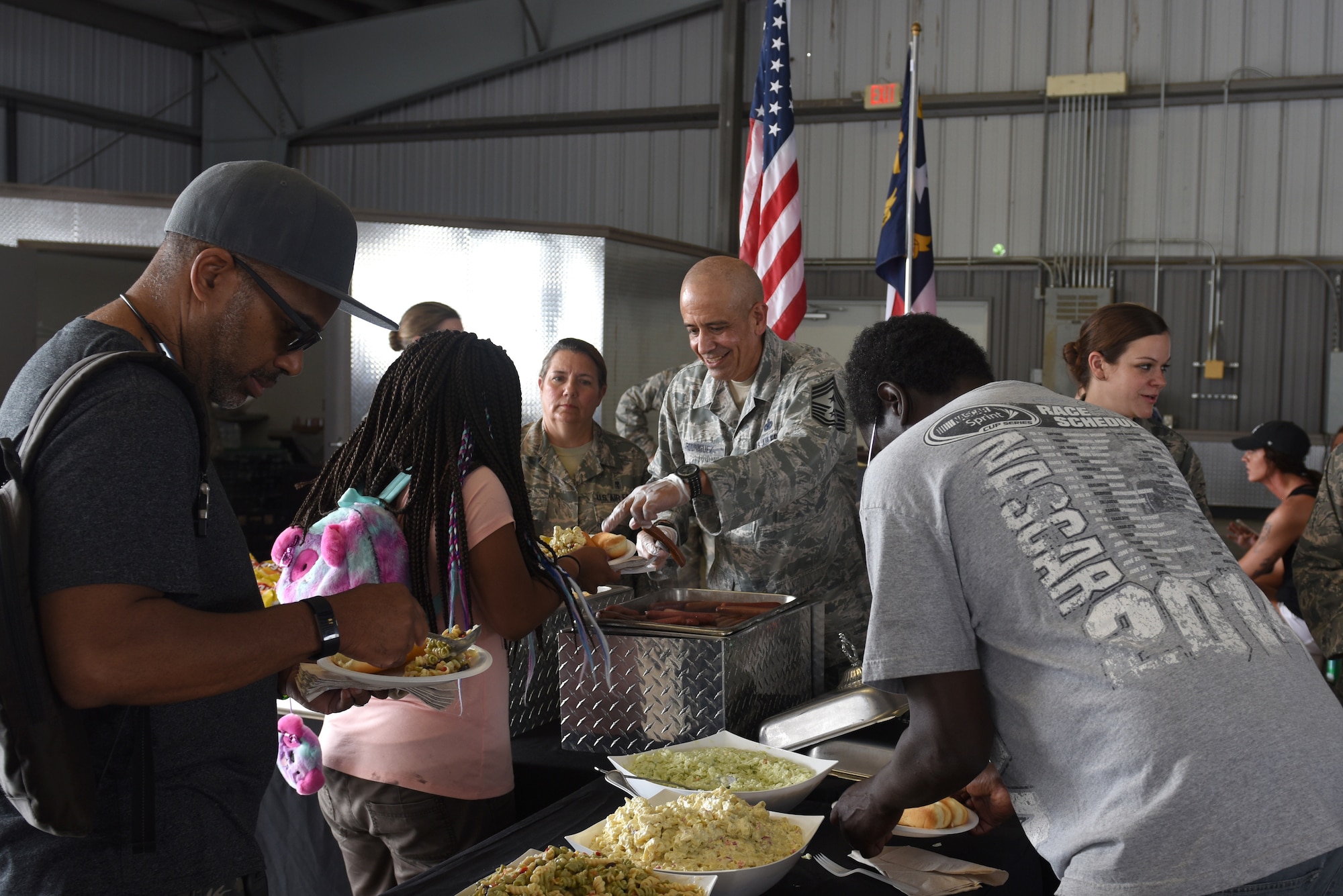 North Carolina National Guard State Command Chief Master Sgt. David Rodriguez (center), serves food to participants and their families at the Z-Max Pavilion, Charlotte N.C., during the annual Special Olympics Day at the Races, May 24, 2018. The Special Olympics Day at the Races is an annual celebration held at the Lowes Motor Speedway and is put on by Vangie Boswell and fourteen sponsors including the NCANG. Members of the NCANG help set-up the event and pass out mementos while mingling with State Special Olympians and their families.(U.S. Air Force photo by Staff Sgt. Laura J. Montgomery/Released)