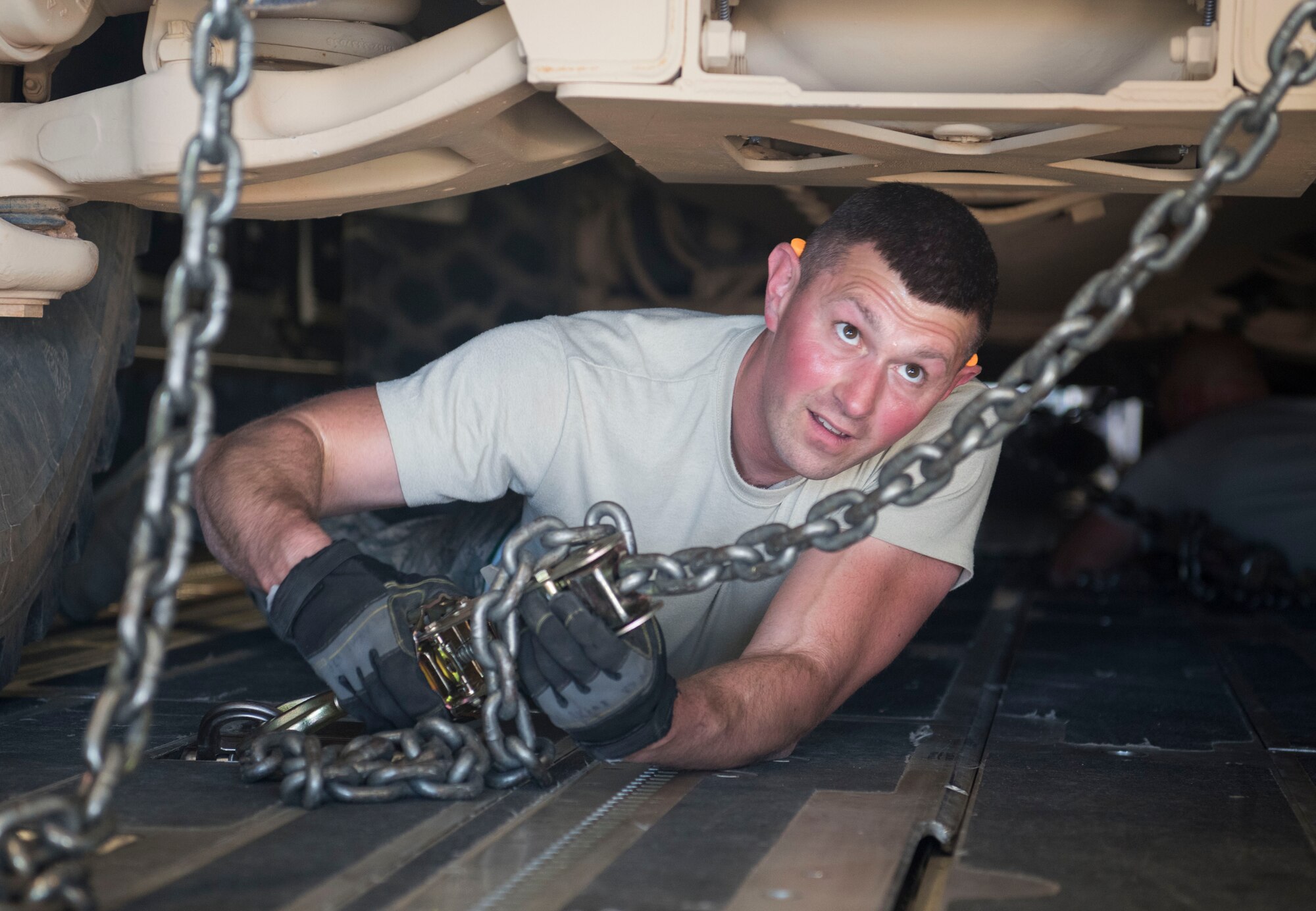 Tech. Sgt. Nicholas Akins, 332nd Expeditionary Logistics Readiness Squadron air transportation specialist, secures a mine-resistant ambush protected vehicle with chains for transportation onto a C-17 Globemaster III at an undisclosed location in Southwest Asia March 7, 2018.
