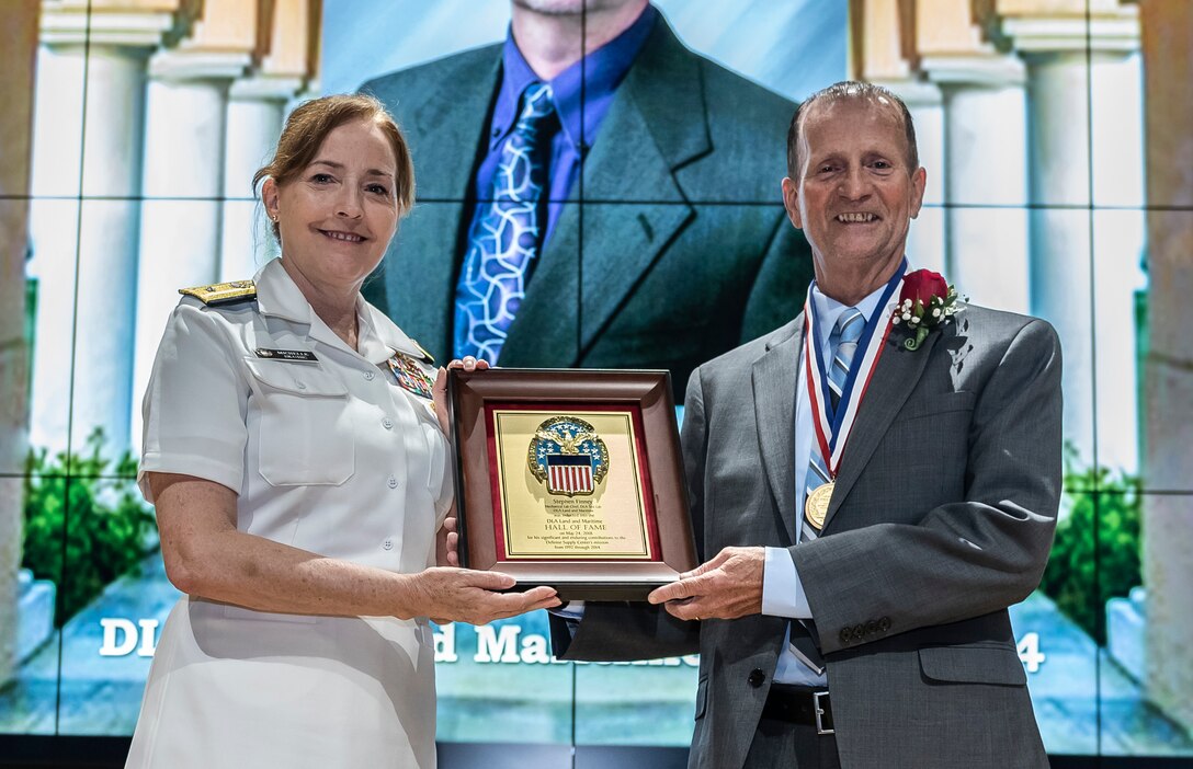 Finney receives a plaque and medal from Defense Logistics Agency Land and Maritime Commander Navy Rear Adm. Michelle Skubic
