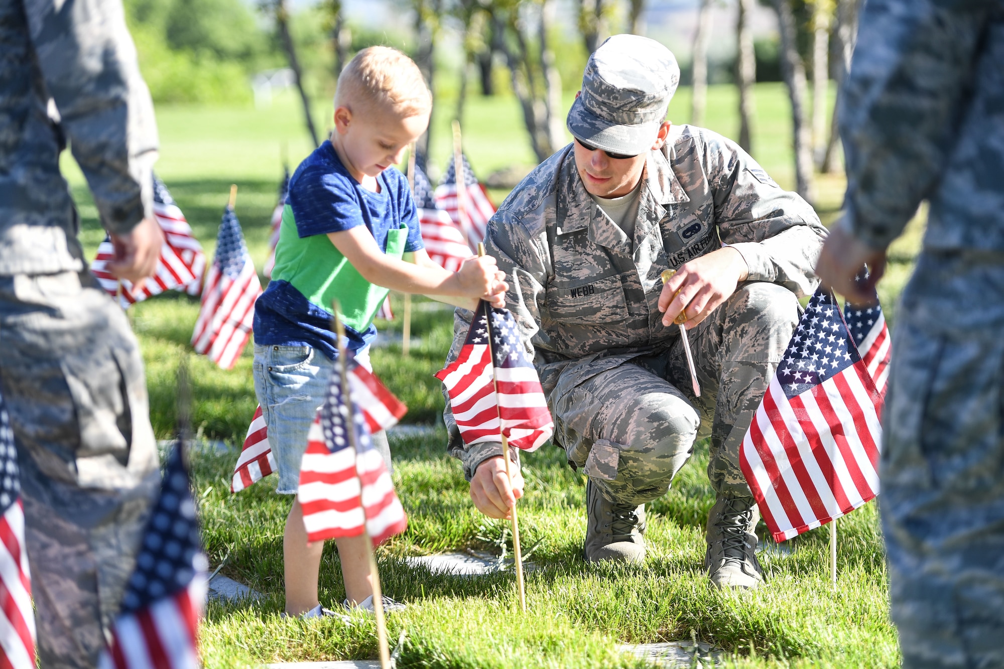 Senior Airman James Webb, 388th Maintenance Squadron, places a flag with Jaxton Gardner, son of Master Sergeant Phillip Gardner, 729th Air Control Squadron, May 26, 2018, at the Veterans Memorial Cemetery at Camp Williams, Utah. Several Airmen from Hill Air Force Base participated in the annual flag laying event over Memorial Day weekend. (U.S. Air Force photo by Cynthia Griggs)