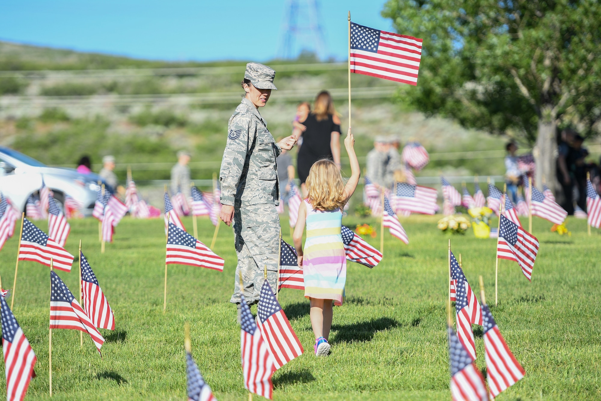 Tech. Sgt. Adrian Villa, 419th Fighter Wing, places a flag with her daughter, Presley Wigman, May 26, 2018, at the Veterans Memorial Cemetery at Camp Williams, Utah. Several Airmen from Hill Air Force Base participated in the annual flag laying event over Memorial Day weekend. (U.S. Air Force photo by Cynthia Griggs)