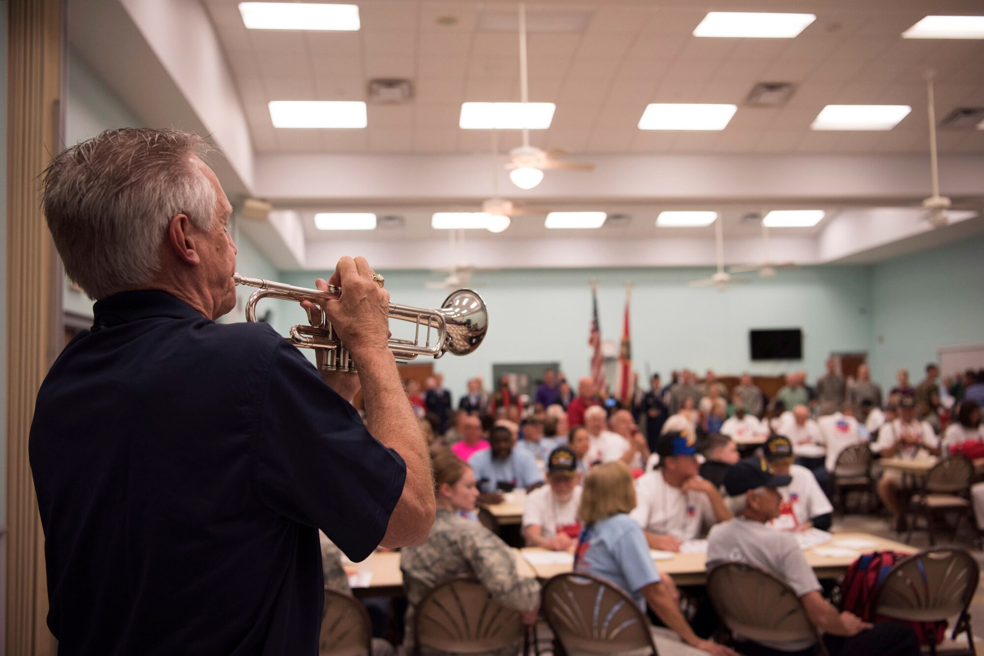 Duke Scales, a volunteer in the Space Coast Honor Flight program, plays morning reveille for all in attendance May 26, 2018 at the Wickham Park Senior Center in Melbourne, Fla. Veterans who served in World War II, the Korean War and the Vietnam War gathered at the senior center to fly to Washington D.C. and visit war memorials dedicated to the sacrifices they made, along with their fellow service members. (U.S. Air Force photo by Airman 1st Class Zoe Thacker)