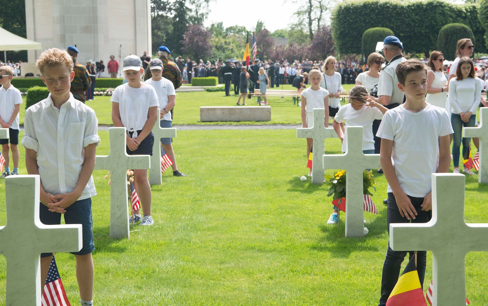 School children from the Municipality of Waregem stand over grave sites at Flanders Field American Cemetery, Belgium, May 27, 2018. Local school children have participated in Memorial Day ceremonies at Flanders Field every year since 1923. (U.S. Air Force photo by Senior Airman Elizabeth Baker)