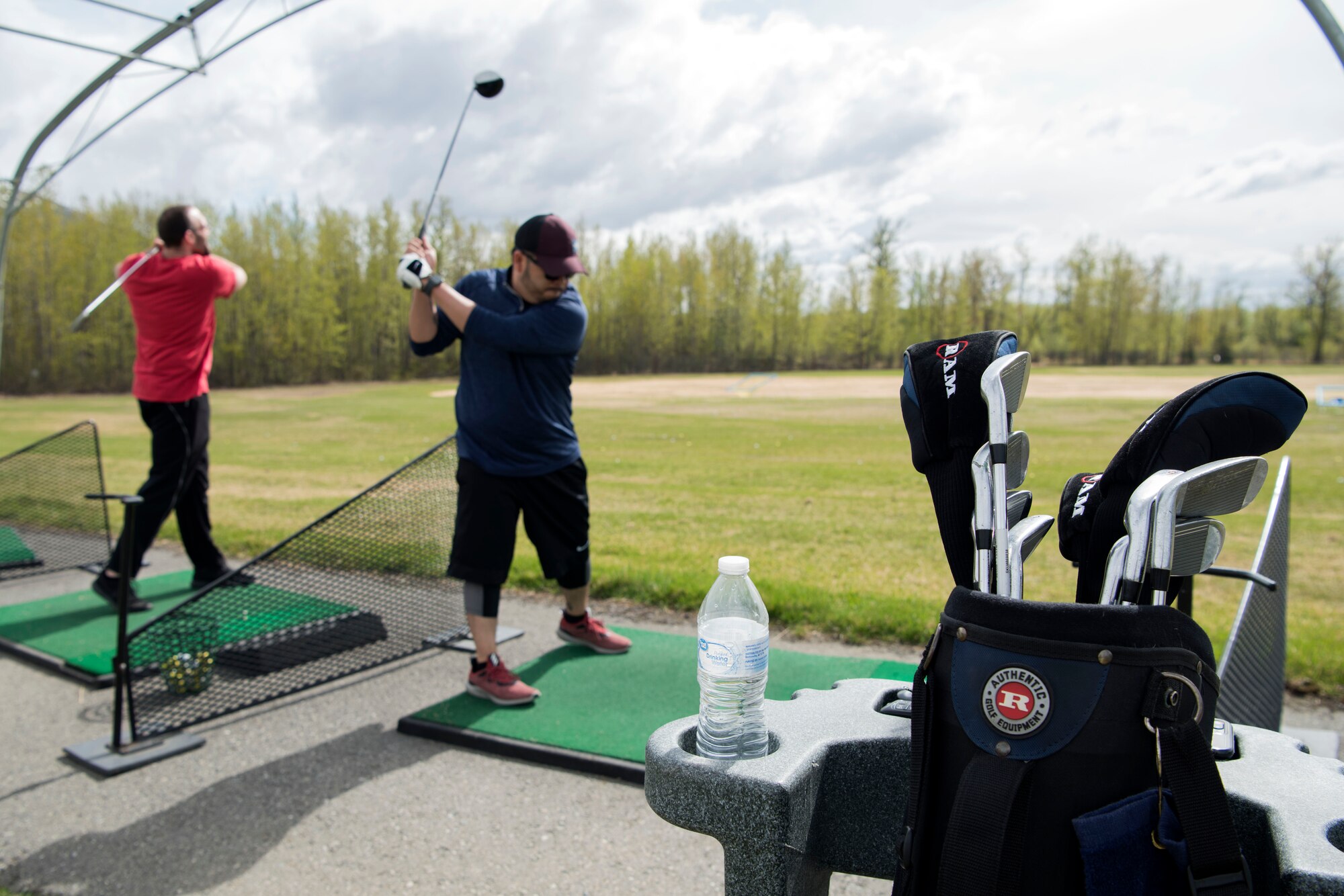Sean Fields and Rommel Reyes practice their golf swings at Moose Run Golf Course driving range at Joint Base Elmendorf-Richardson, Alaska, May 21, 2018. Both Fields and Reyes have been using the course for more than a year and have experienced the relaxed environment and tournaments it has to offer.