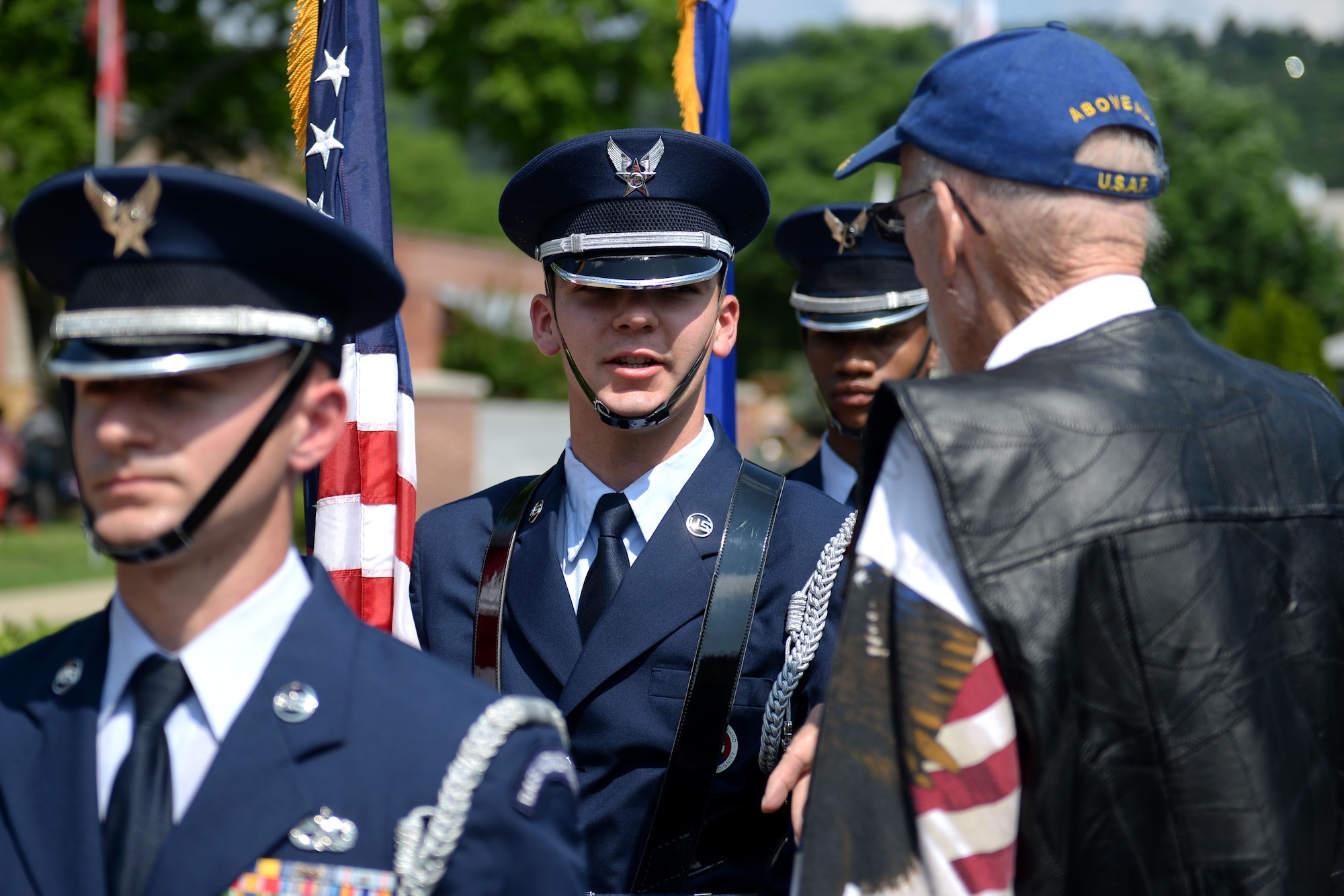 A man in the Air Force honor guard service dress uniform speaks with an elderly gentleman wearing an Air Force ball cap.
