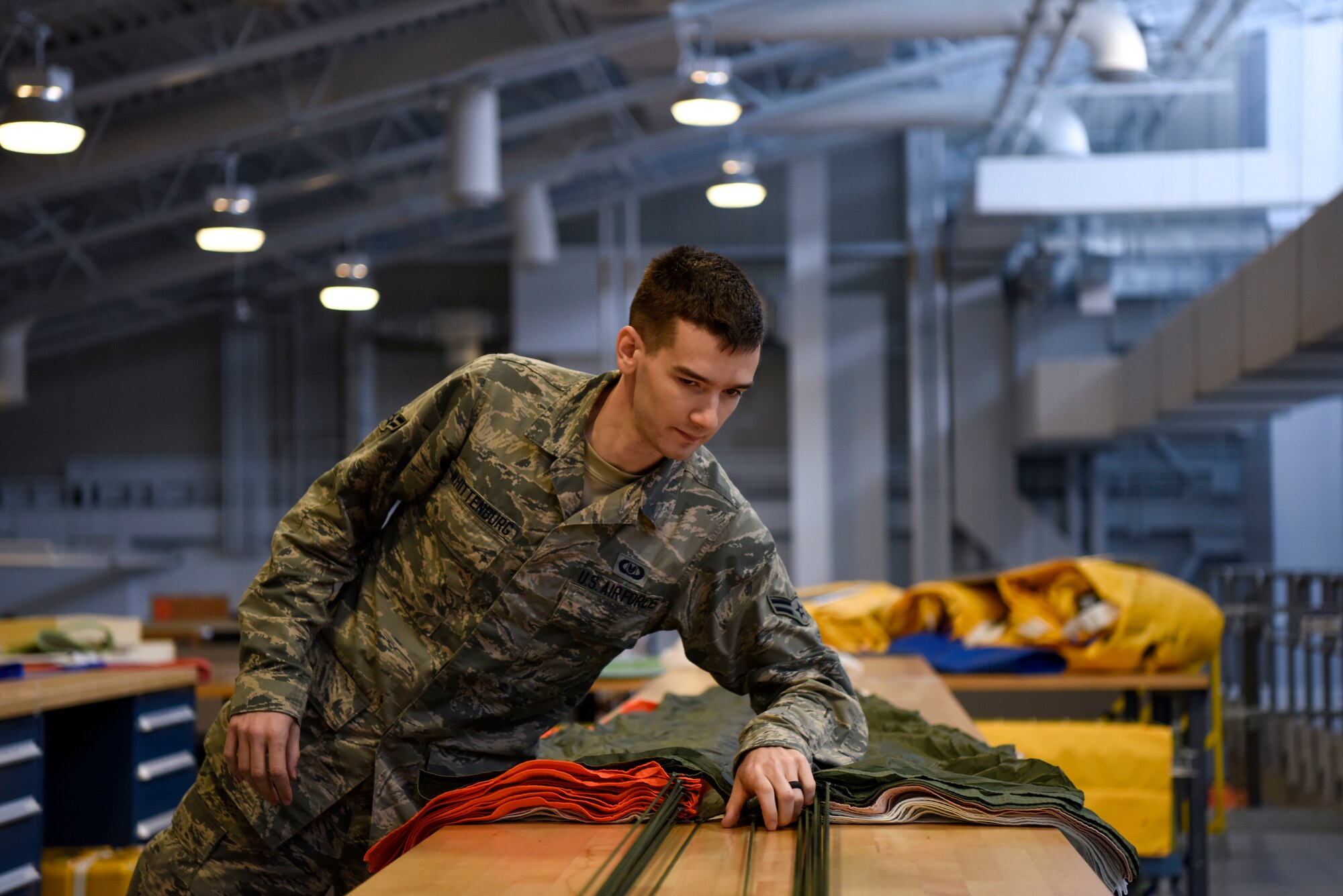 Airman 1st Class Cody Whittenburg, 436th Operations Support Squadron aircrew flight equipment apprentice, inspects and packs a parachute May 23, 2018, at Dover Air Force Base, Del. Parachutes are folded following a tedious process to ensure proper function during emergency aircraft egress. (U.S Air Force photo by Airman 1st Class Zoe M. Wockenfuss)