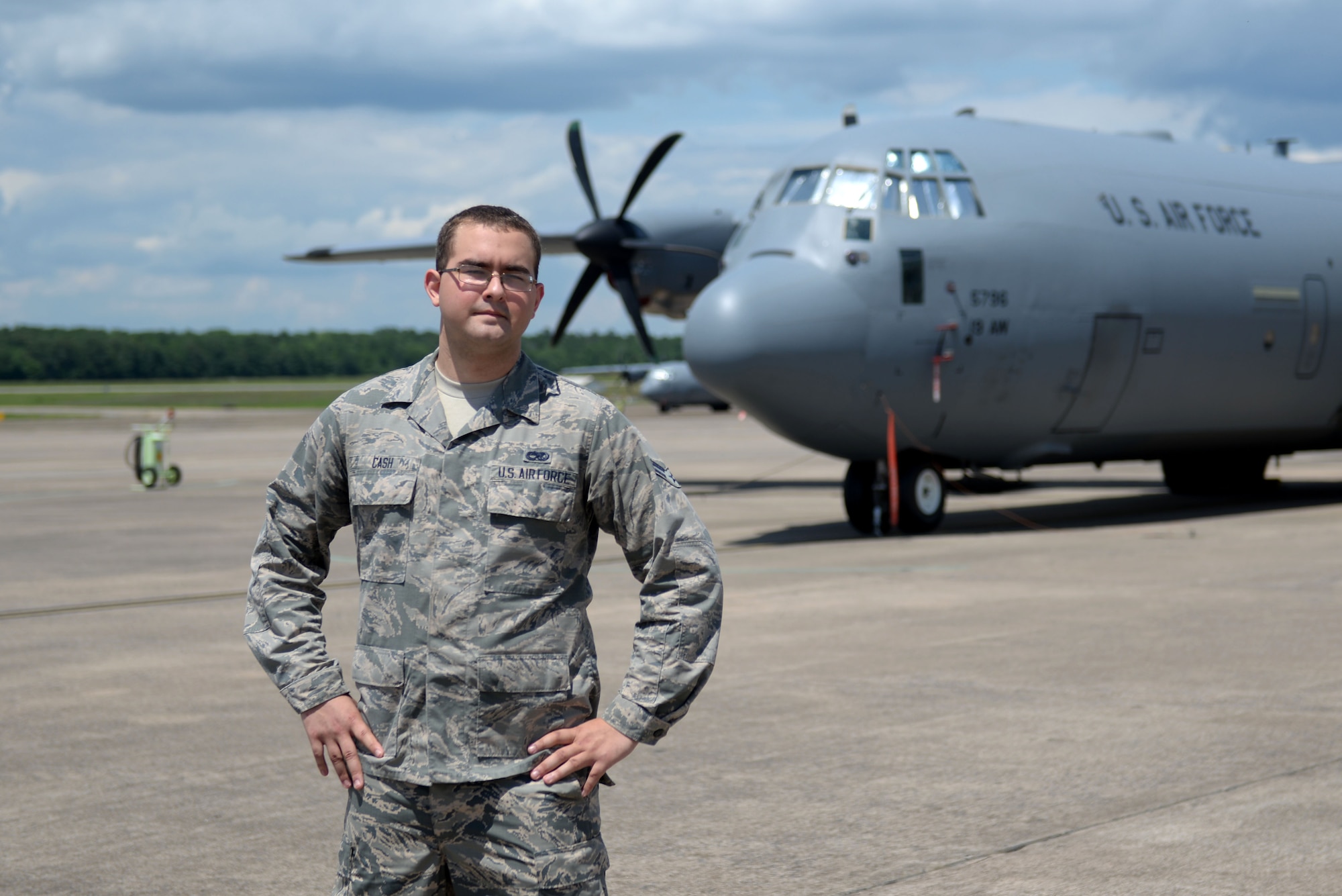 A man in the Airman Battle Uniform stands with his hands on his hips in front of a C-130J.
