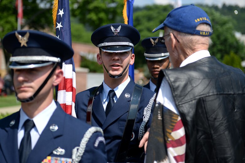 A man in the Air Force honor guard service dress uniform speaks with an elderly gentleman wearing an Air Force ball cap.