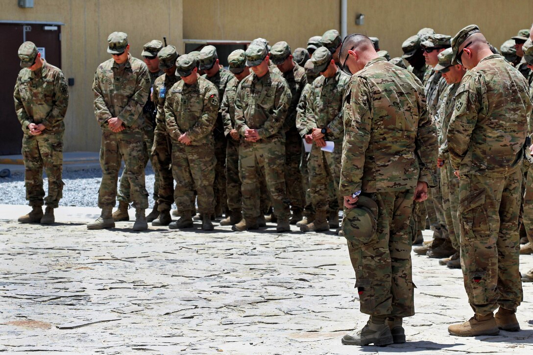 Soldiers and leaders bow their heads during an opening prayer.