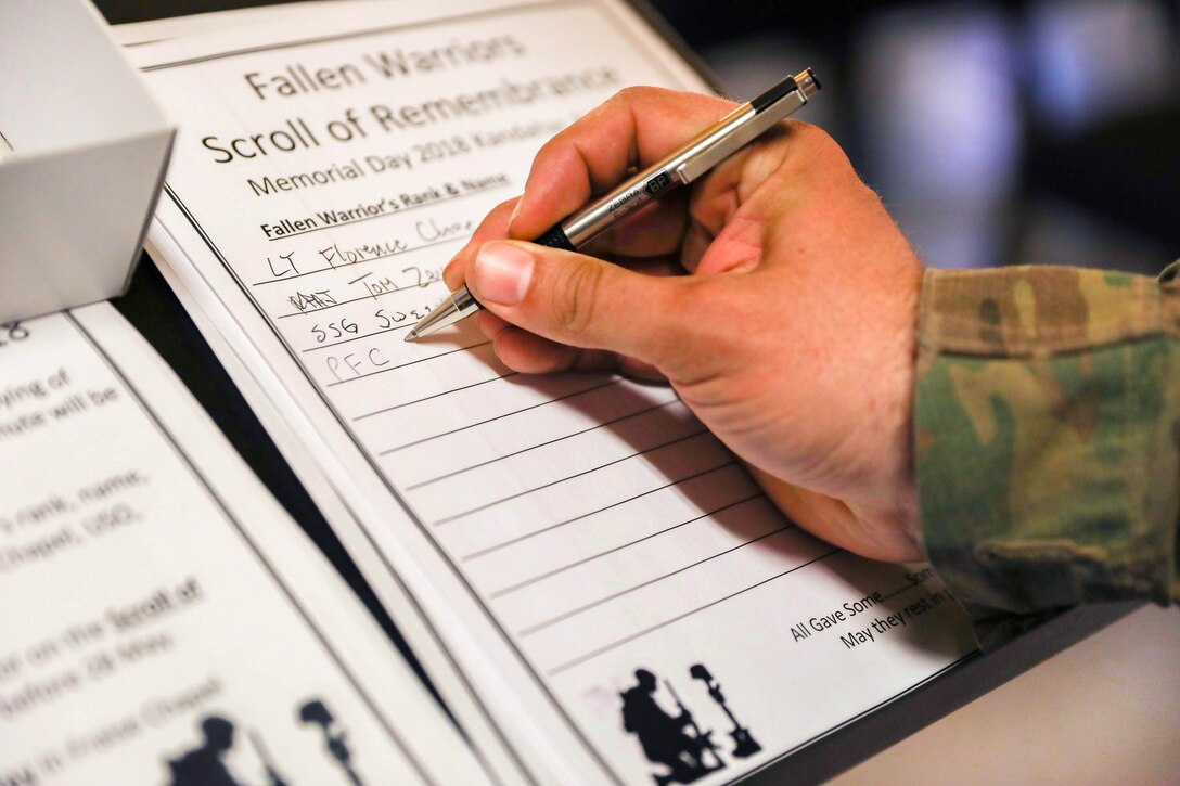A soldier writes the name of a fallen warrior in a guest book in the chapel.