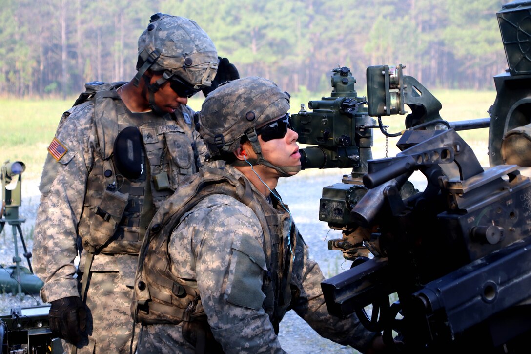A soldier checks the target grid coordinates on a howitzer.
