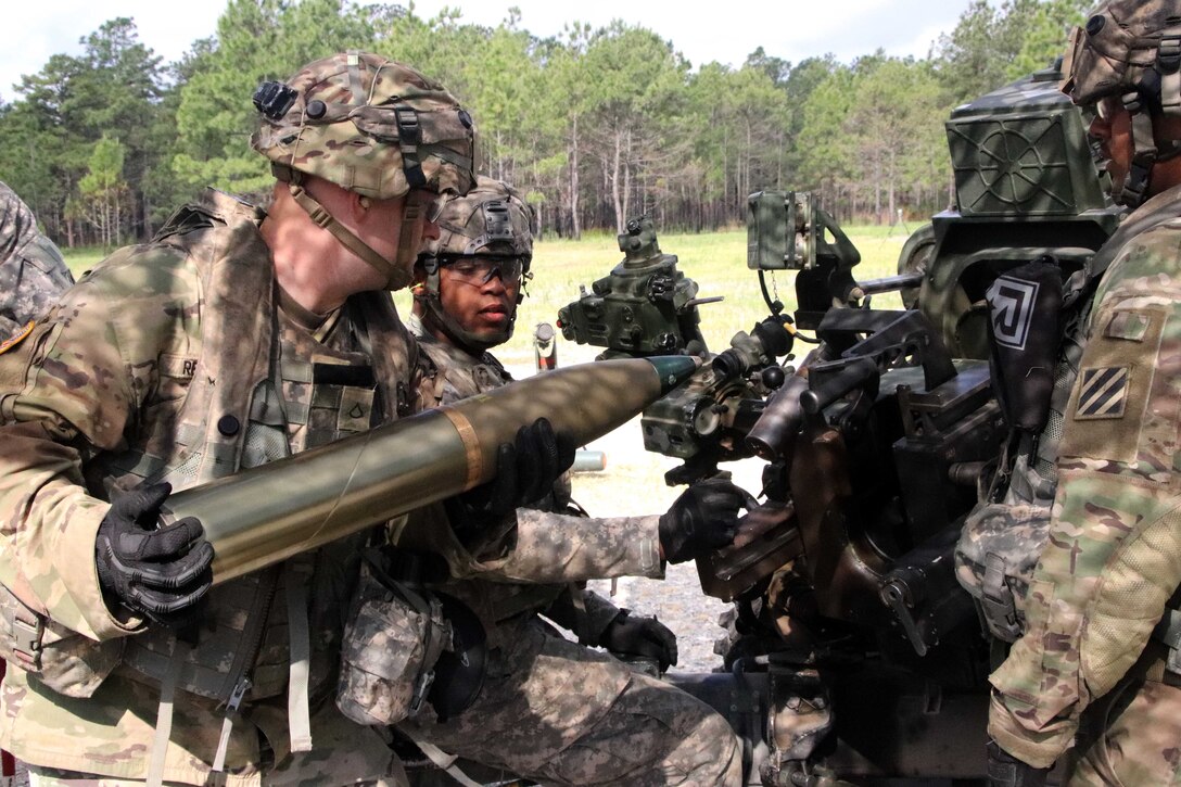 Soldiers load a round into a howitzer during a live-fire exercise.