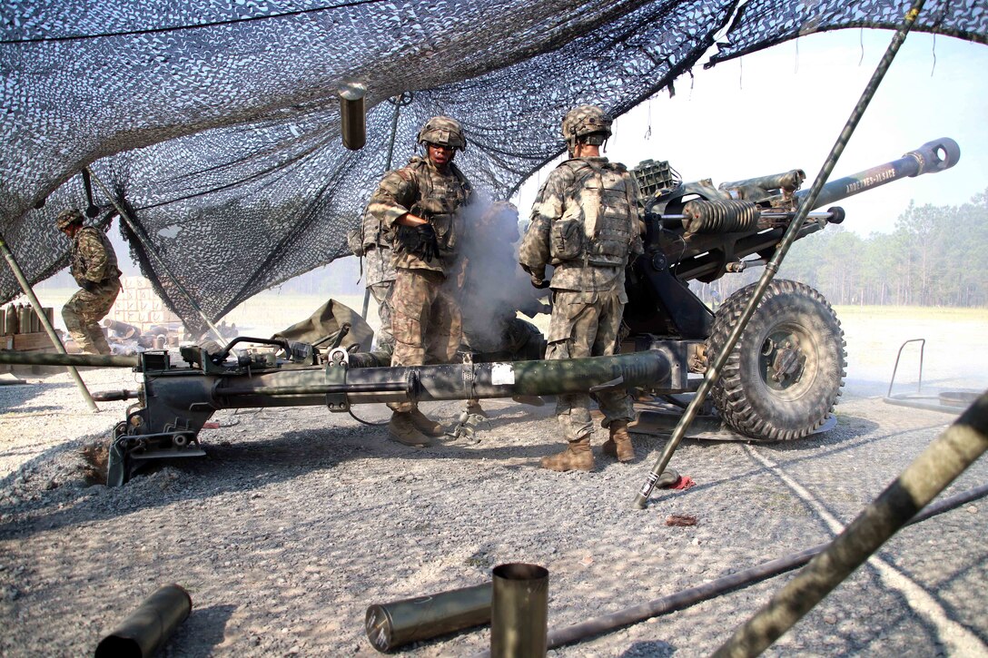 A soldier tosses an empty casing during a howitzer live-fire exercise.